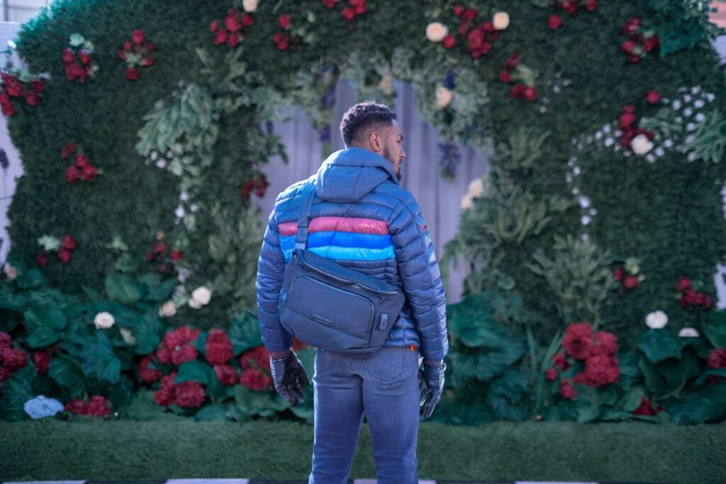 Best sling bag Alpaka Bravo Sling Max V2 showcasing vibrant puffer jacket with nature backdrop.
