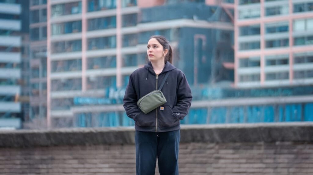Best sling bag Alpaka Flight Sling urban scene with thoughtful woman in casual attire and modern buildings.