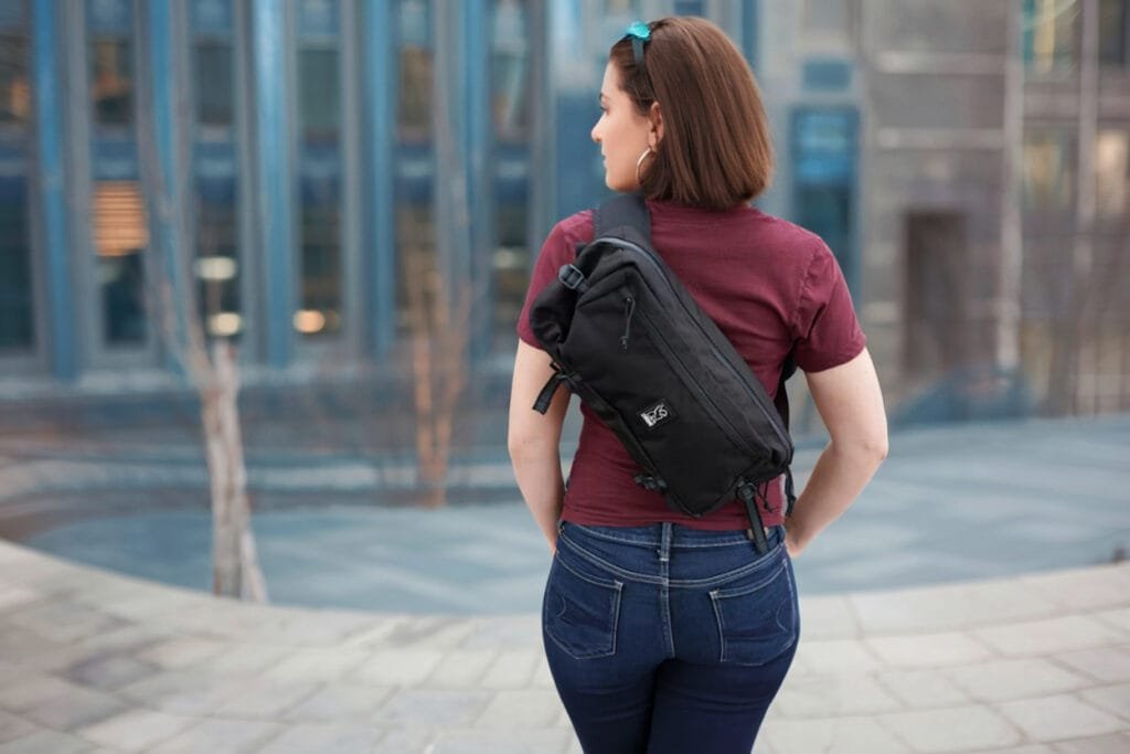 Best sling bag Chrome Industries Kadet nylon messenger bag showcased in urban setting with modern architecture.