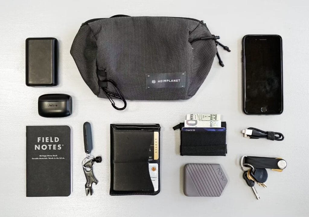 Best sling bag everyday carry layout featuring a pouch, phone, power bank, notebook, and essentials.