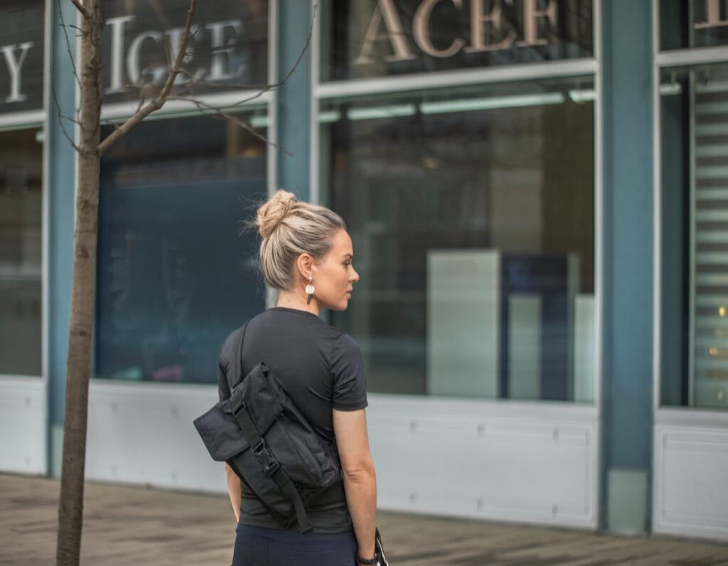 Best sling bag Mission Workshop Spar Sling on woman with modern architecture and nature backdrop.