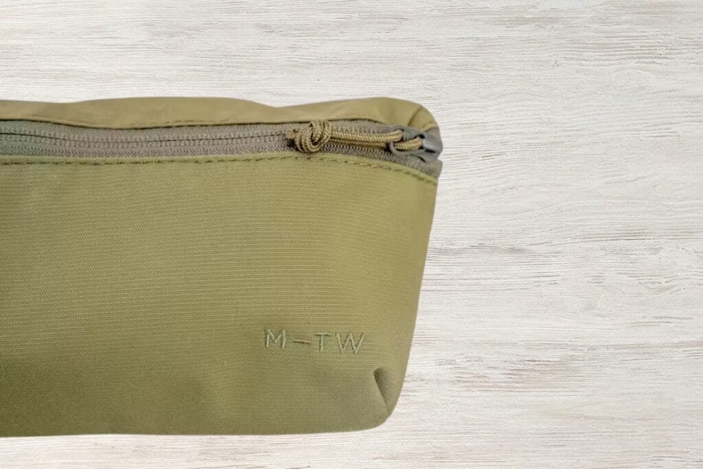 Best sling bag MUJI pouch in beige nylon with subtle sheen on light wooden tabletop.