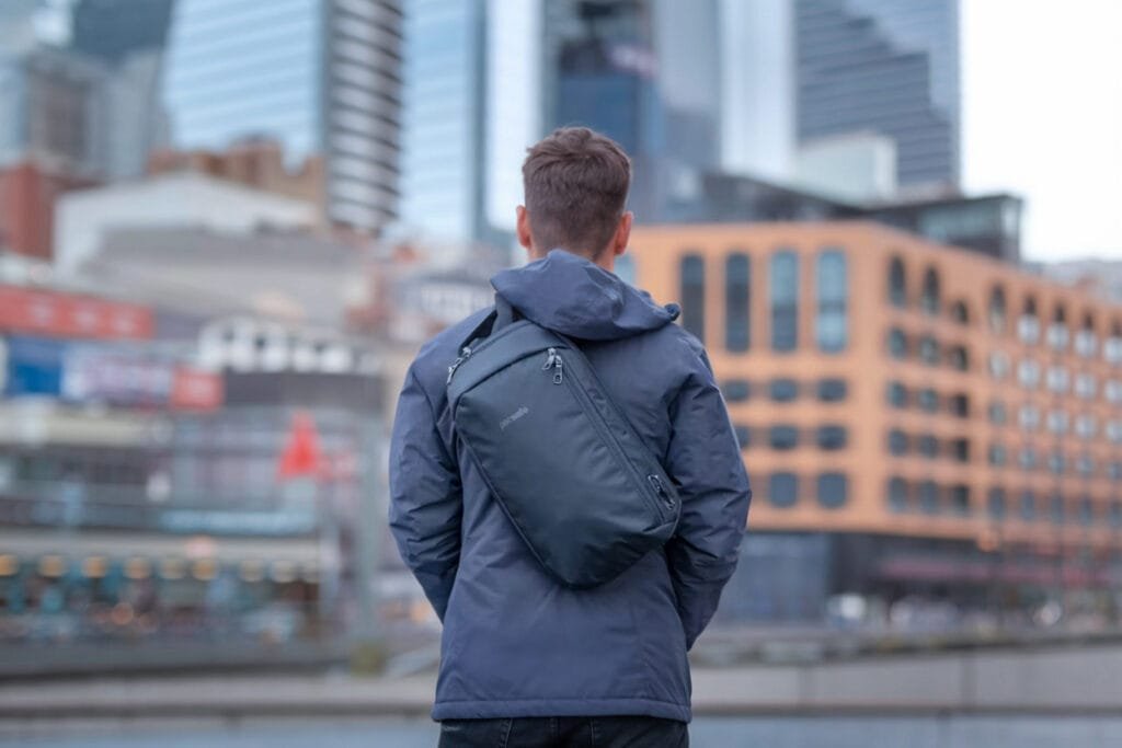 Best sling bag Pacsafe Vibe 325 anti-theft sling pack with city skyline background and modern skyscrapers.