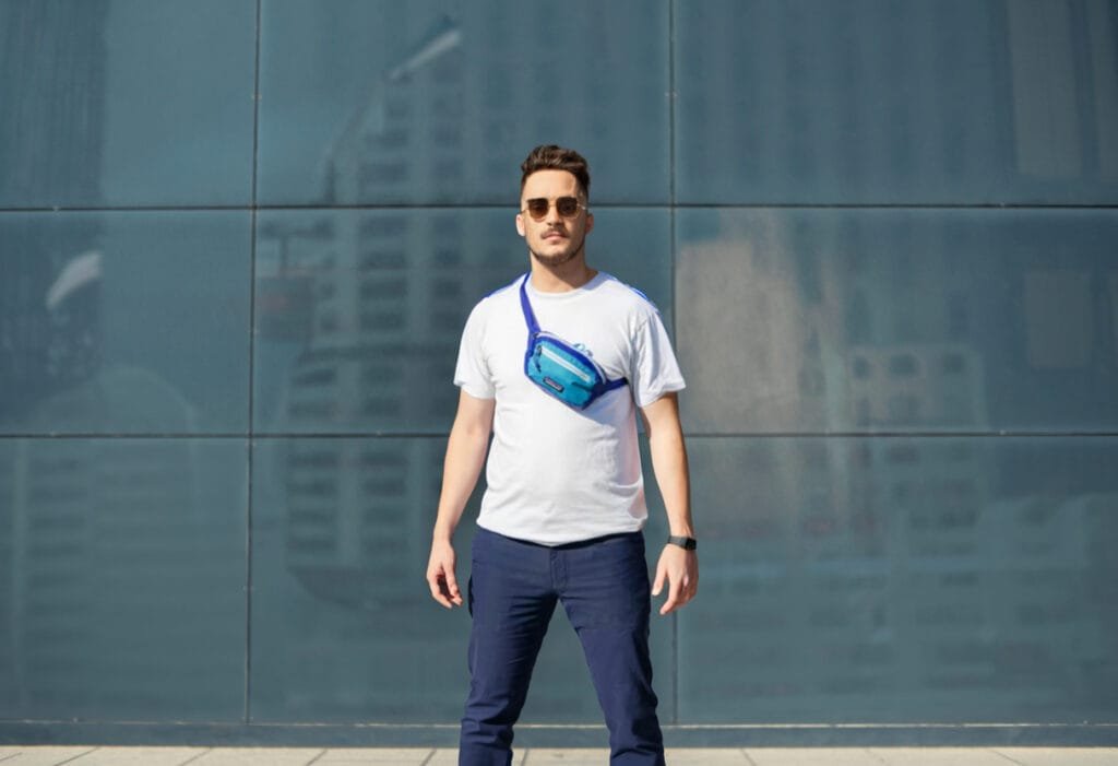 Best sling bag viewed on man in casual stylish outfit outside a modern glass building in daylight.