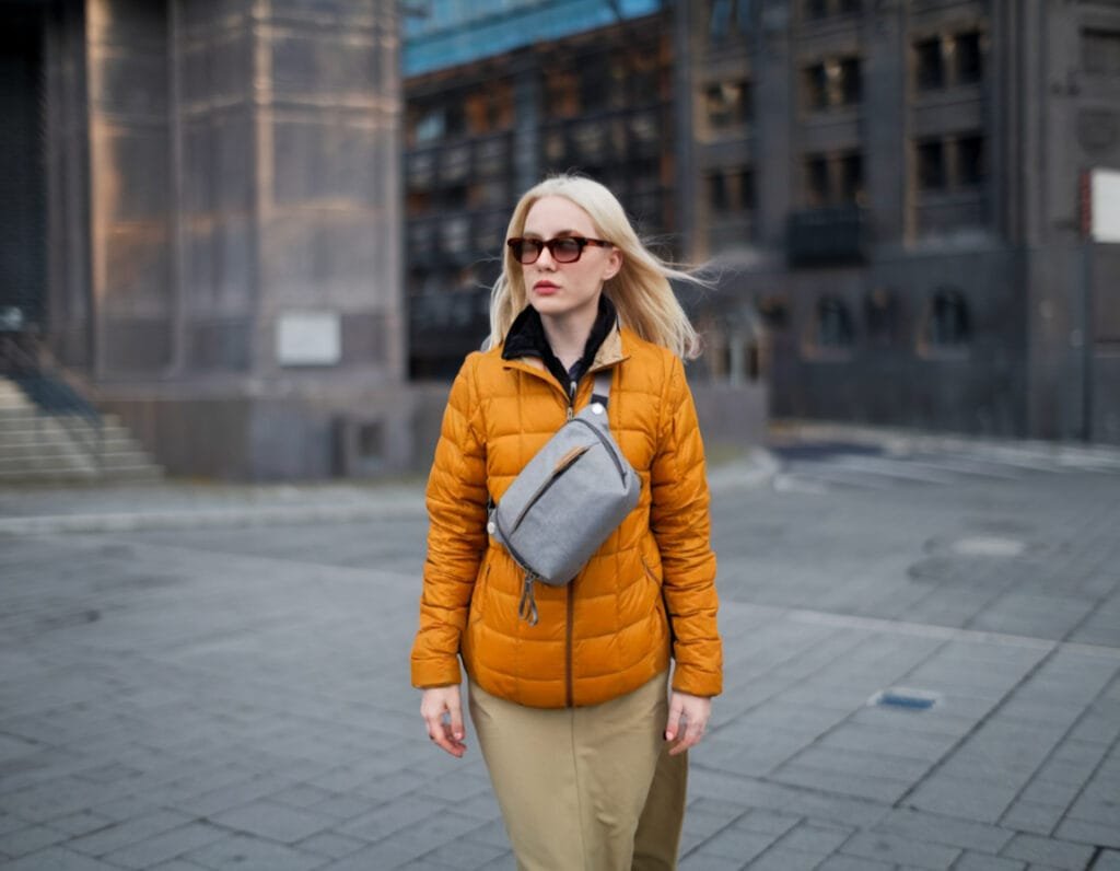 Best sling bag Peak Design Everyday Sling 3L V2 worn stylishly with vibrant urban fashion in cityscape.