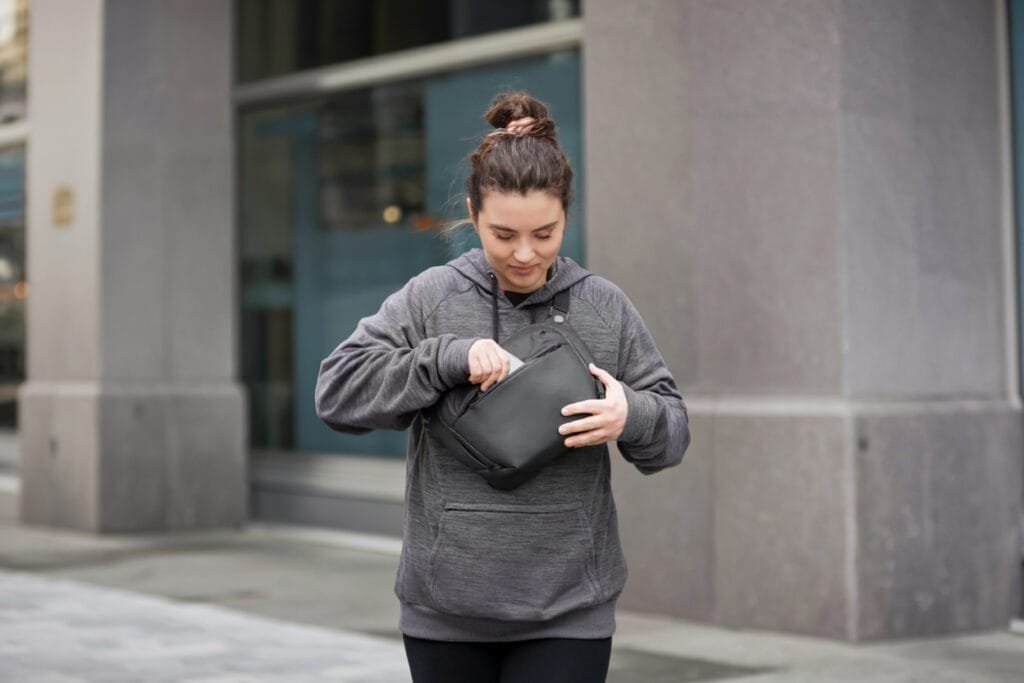Best sling bag lifestyle view with woman organizing black Peak Design Everyday Sling 6L V2.