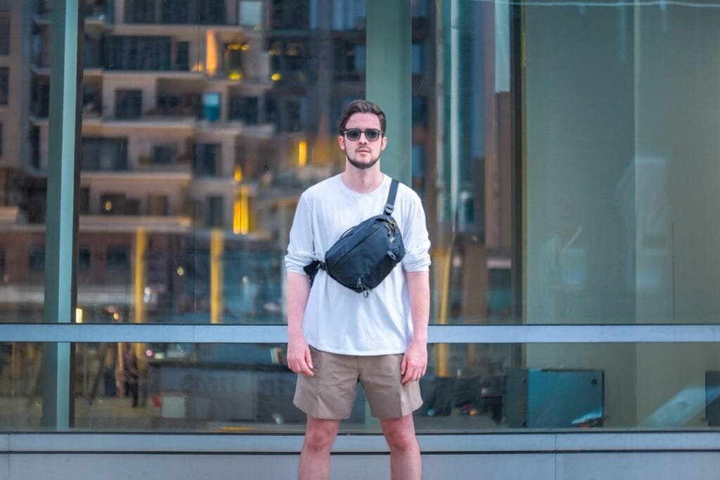Best sling bag Peak Design Outdoor Sling 7L worn by man in urban cityscape, modern and stylish.
