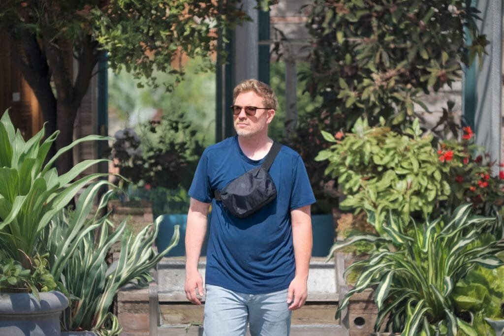 Best sling bag Tortuga Travel Sling features comfortable design and lush garden stroll setting.