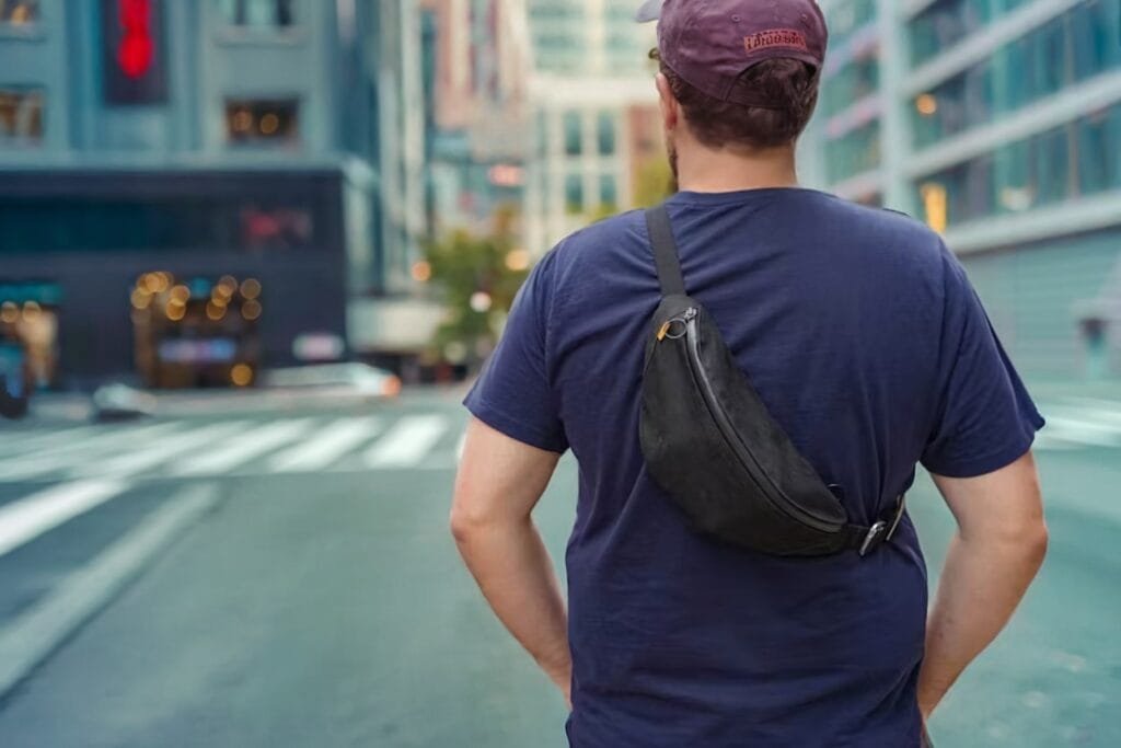 Best sling bag showcase with person wearing Trakke Banana Crossbody Bag in vibrant urban setting.