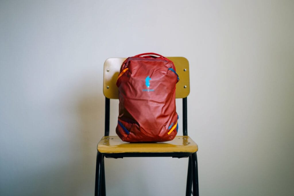 Best Travel Backpack Cotopaxi Allpa 35L on wooden school chair, showcasing vibrant design and functionality.