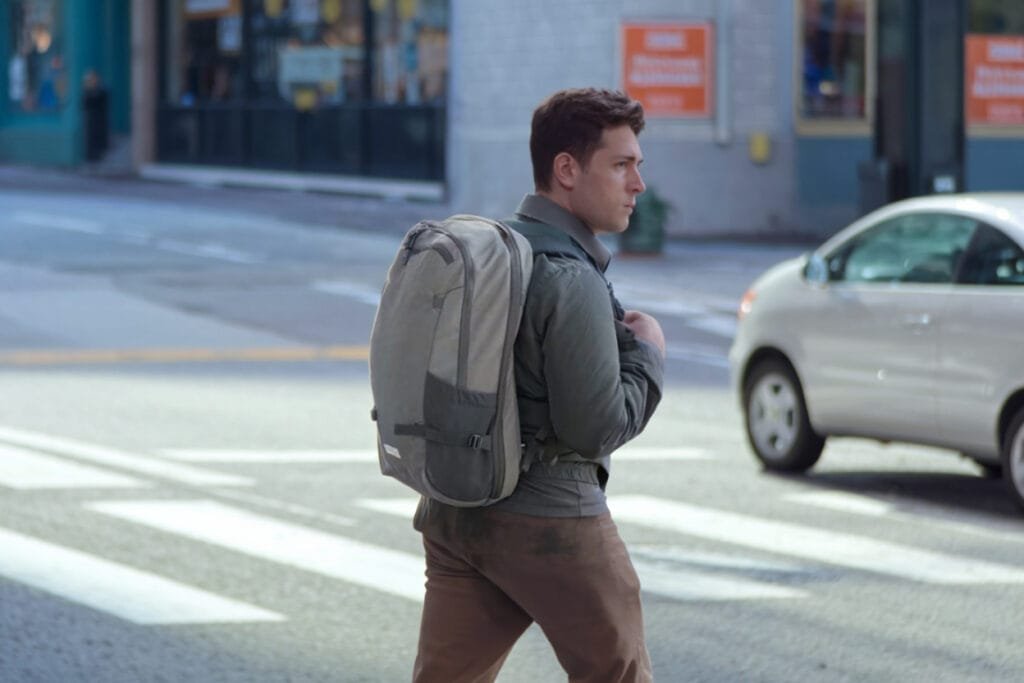 Best travel backpack Heimplanet Travel Pack 34L V2 showcased in urban environment crossing street.