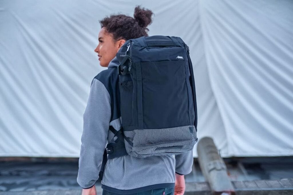 Best travel backpack Matador Globerider45 showcased outdoors with casual jacket and blurred urban backdrop.