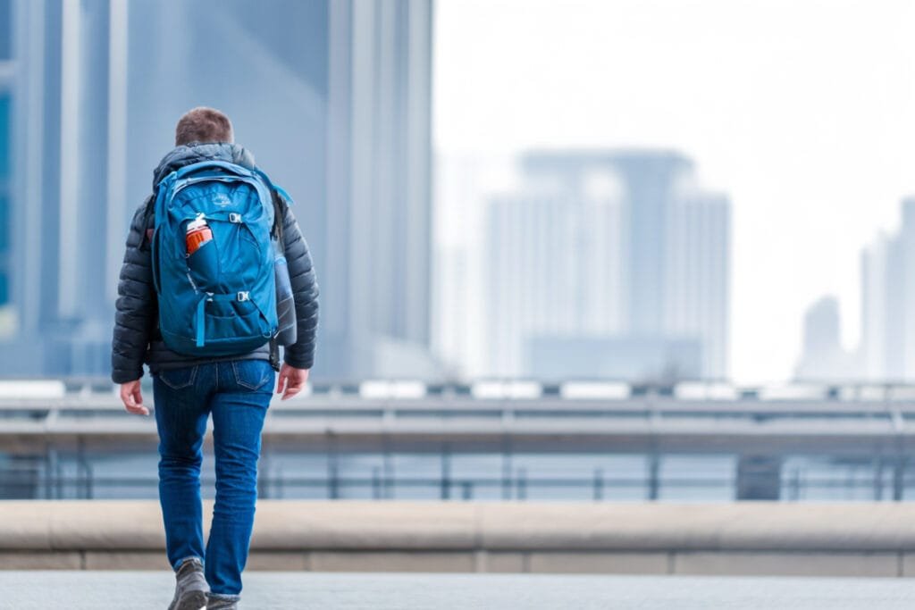 Best travel backpack Osprey Fairview 40 showcased in urban setting with person exploring city skyline.