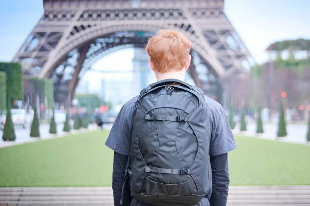 Best travel backpack Osprey Farpoint 40 showcased in Paris, facing Eiffel Tower amid lush gardens.