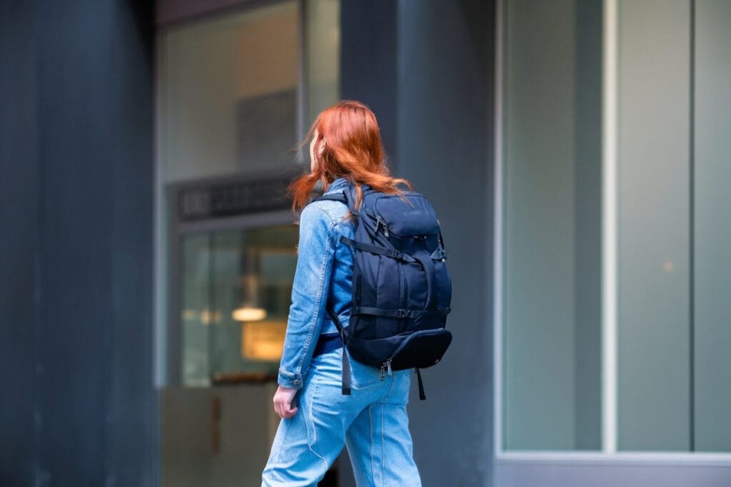 Best travel backpack Pacsafe Venturesafe EXP35: stylish design on a city street with red-haired individual.
