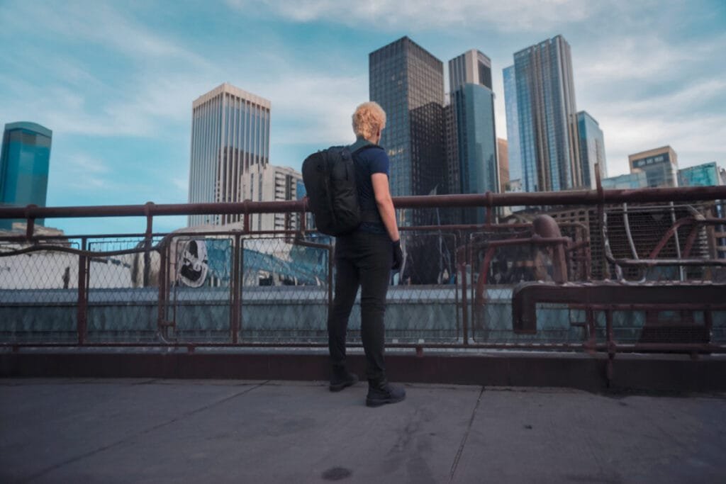 Best travel backpack Peak Design Travel Backpack 45L on rooftop overlooking a vibrant cityscape.