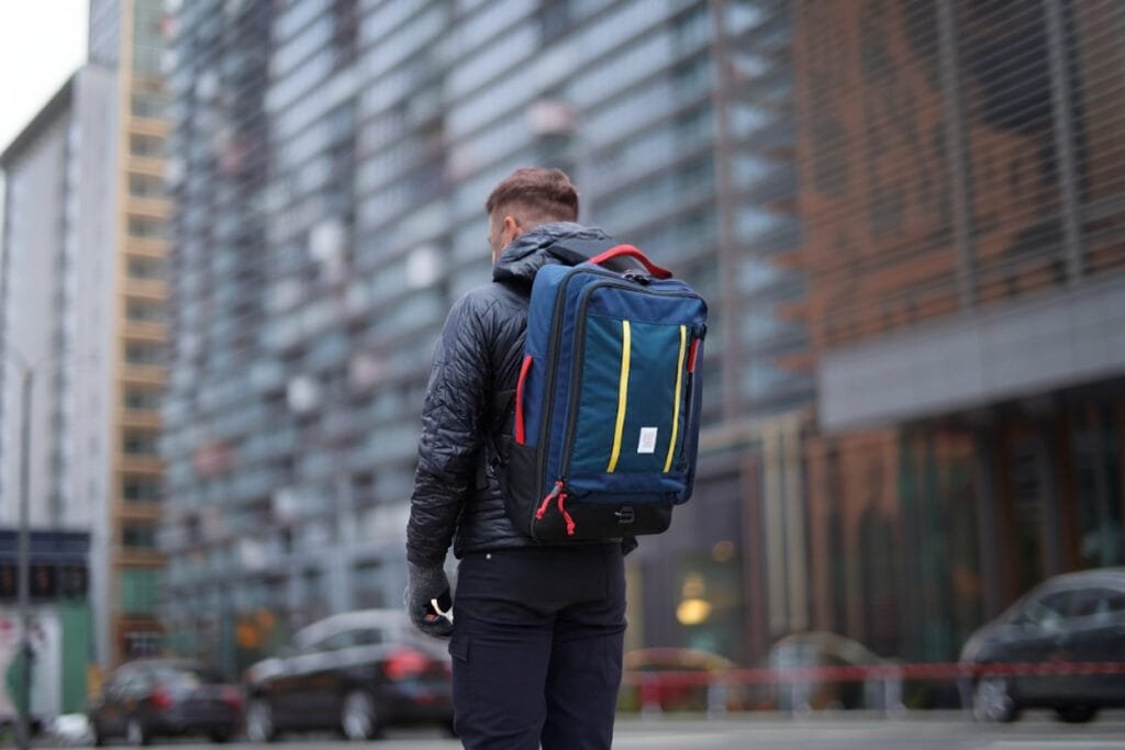 Best travel backpack Topo Designs Global Travel Bag 40L on city street with modern architecture.
