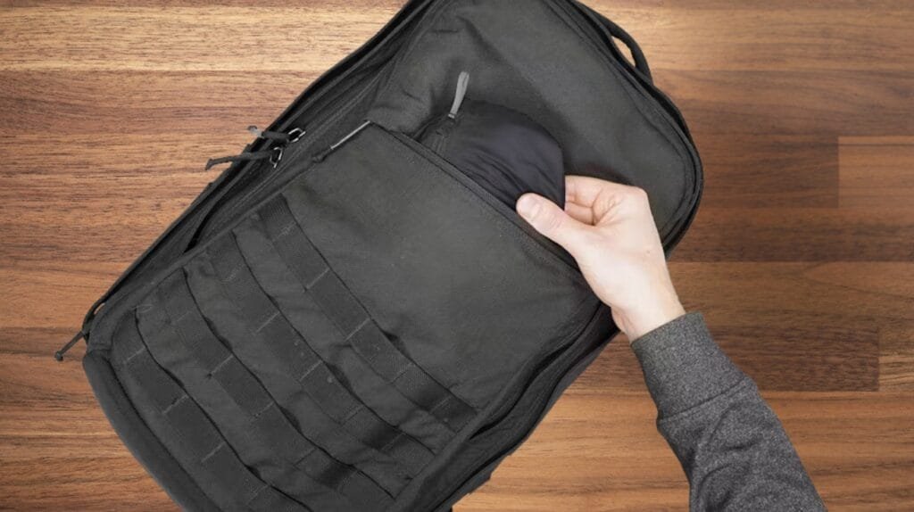 Goruck GR2 40L review showcasing accessible design and functionality, featuring gray-sleeved hand interacting with backpack.