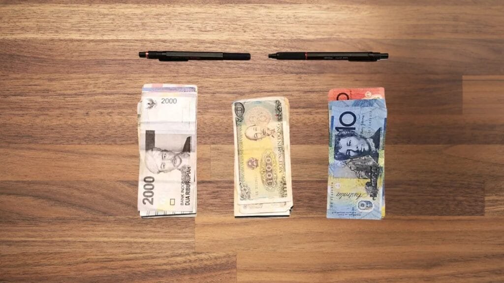 Goruck Gr2 40L review showcasing international banknotes with diverse colors and portraits on wood surface.