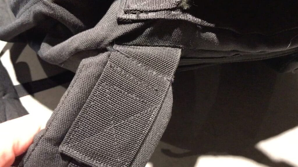 Goruck GR2 40L shoulder strap detail showcasing reinforced stitching with durable nylon fabric and hand interaction.
