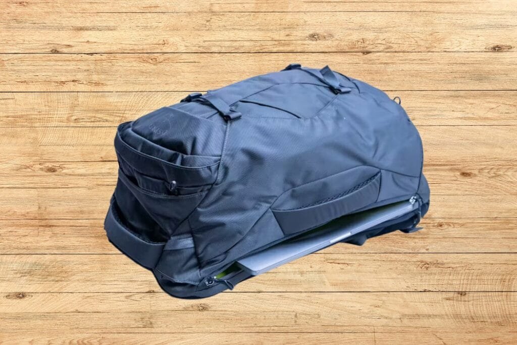 Osprey Farpoint 40 duffel bag with spacious compartments, adjustable straps, and durable design against wood background.