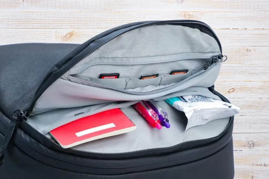 Peak Design Travel Backpack interior view with organized essentials including notebook, pens, and storage pockets.